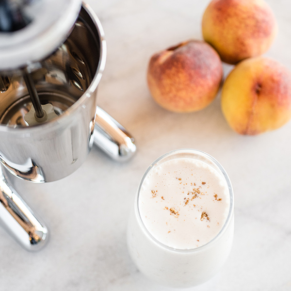 Peach Cobbler milkshake in a glass next to peaches